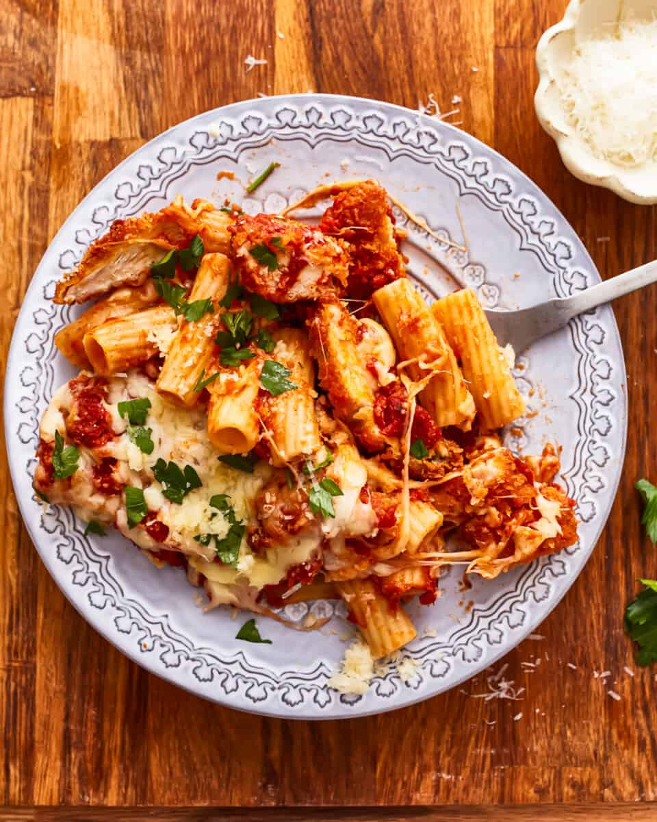 A plate of chicken parmigiana on a wooden table.