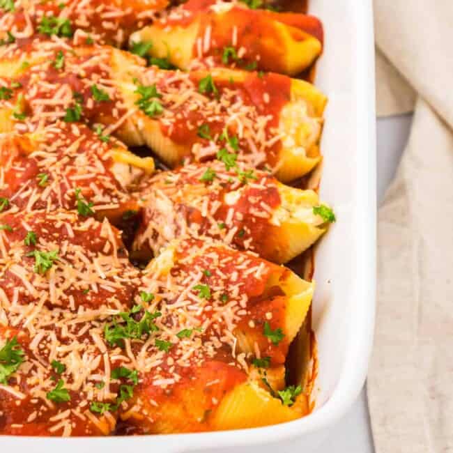 Stuffed shells with sauce and parmesan cheese in a white baking dish.