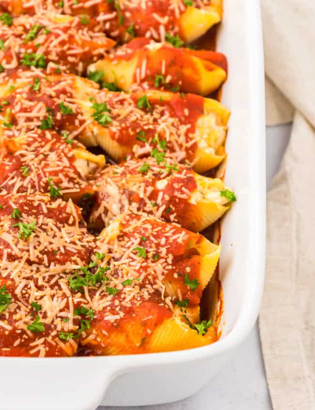 Stuffed shells with sauce and parmesan cheese in a white baking dish.