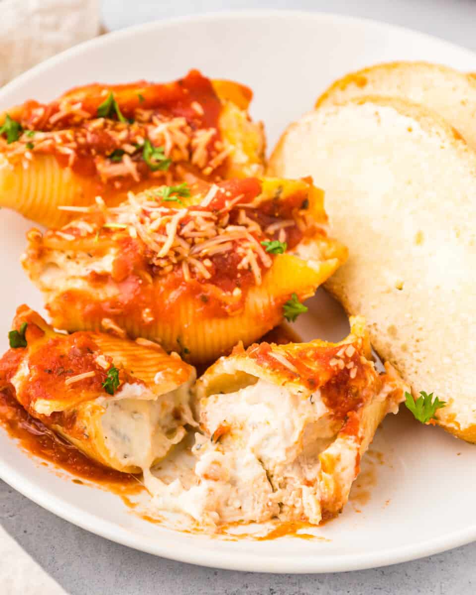 Stuffed shells with chicken on a plate with bread and sauce.