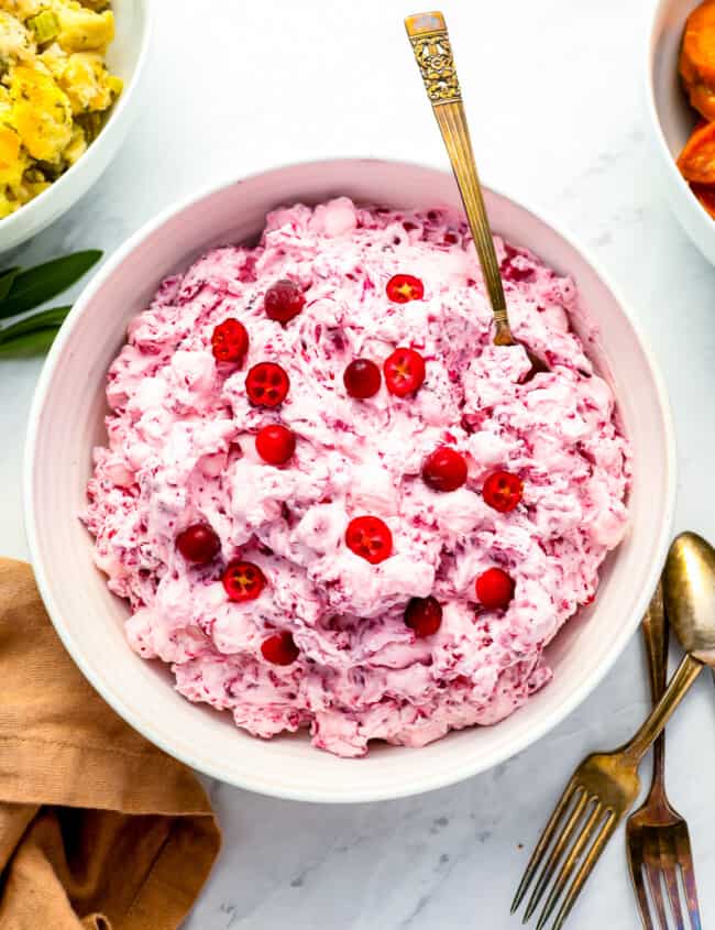 A bowl of cranberry dip with cranberries and carrots.