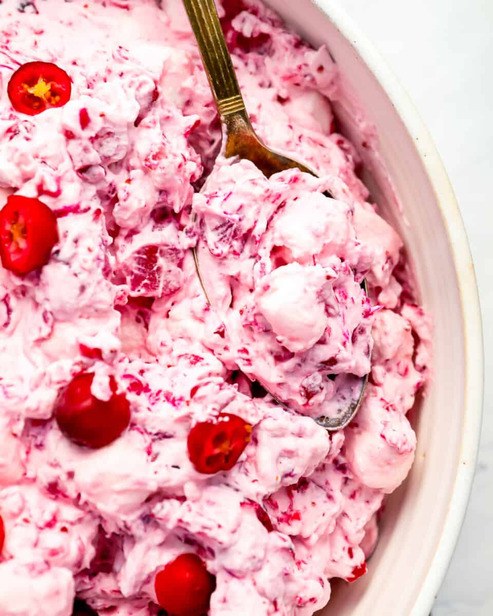 A bowl of cranberry fluff with a spoon.