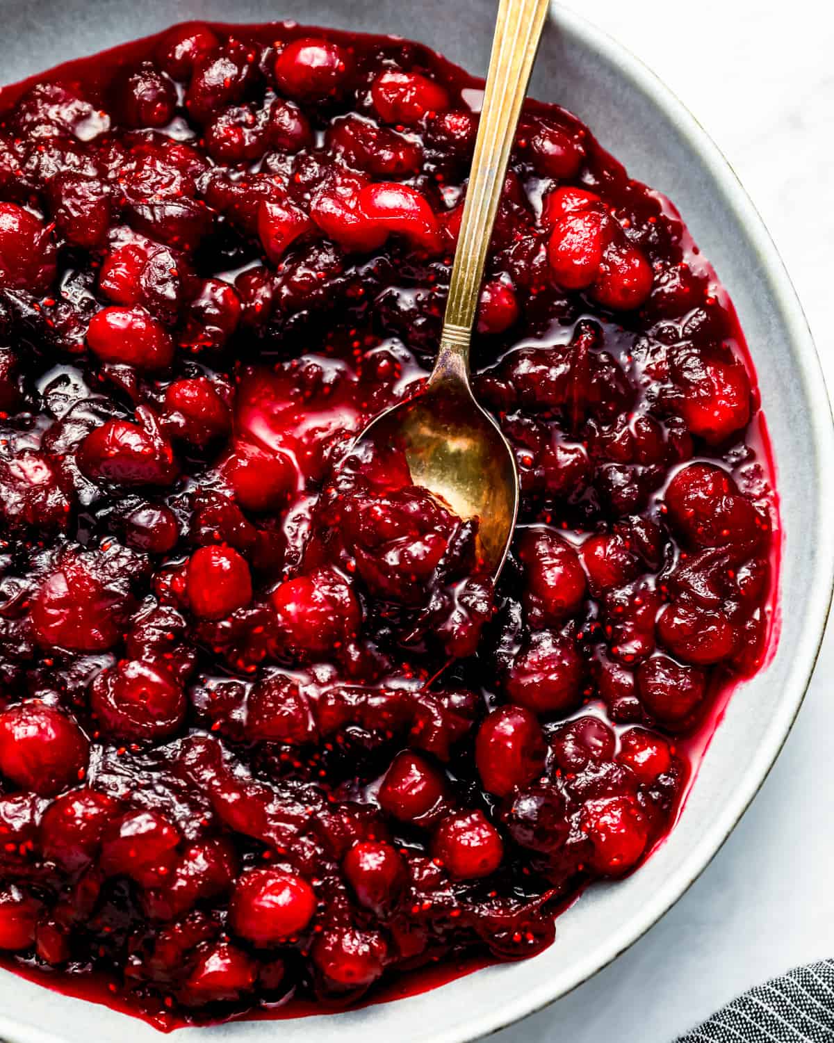 Whole berry cranberry sauce in a bowl with a spoon.