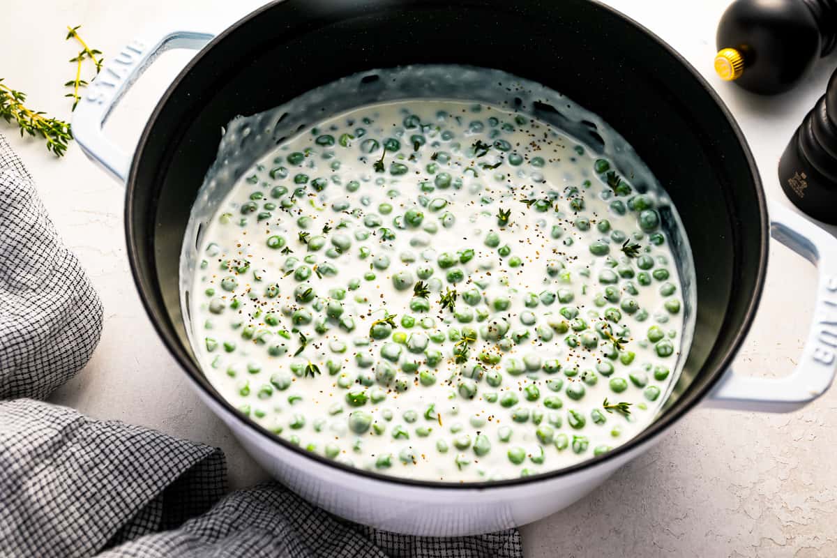 Peas in white cream sauce in a dutch oven.