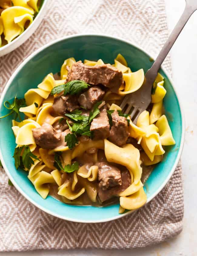 Beef stroganoff in a blue bowl with a fork.