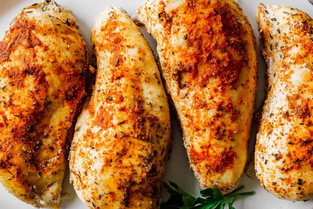 up close crockpot chicken breasts on white platter.