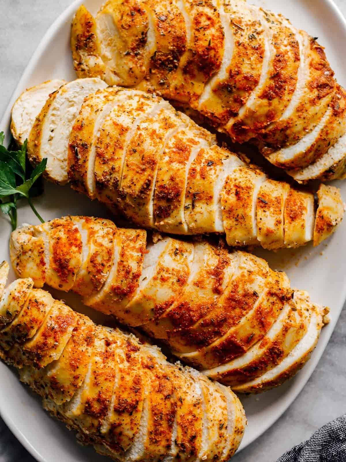 overhead sliced crockpot chicken breasts with spice rub on white plate