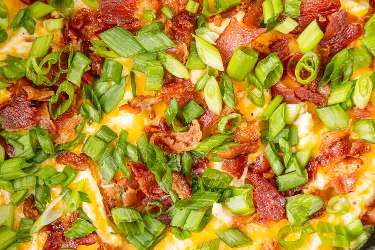 close up view of cheesy chicken with bacon and scallions.