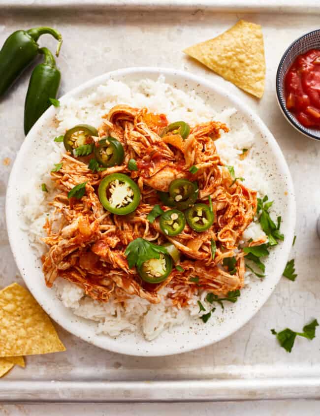 A bowl of rice with chicken and jalapenos.