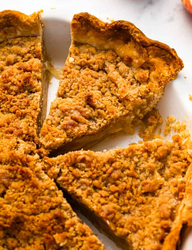 A slice of apple pie with a crumb topping on a plate.