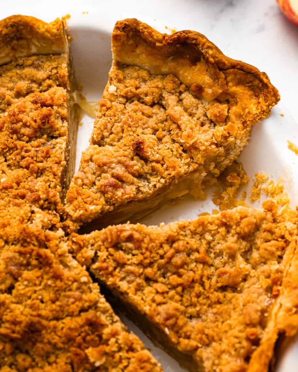 A slice of apple pie with a crumb topping on a plate.