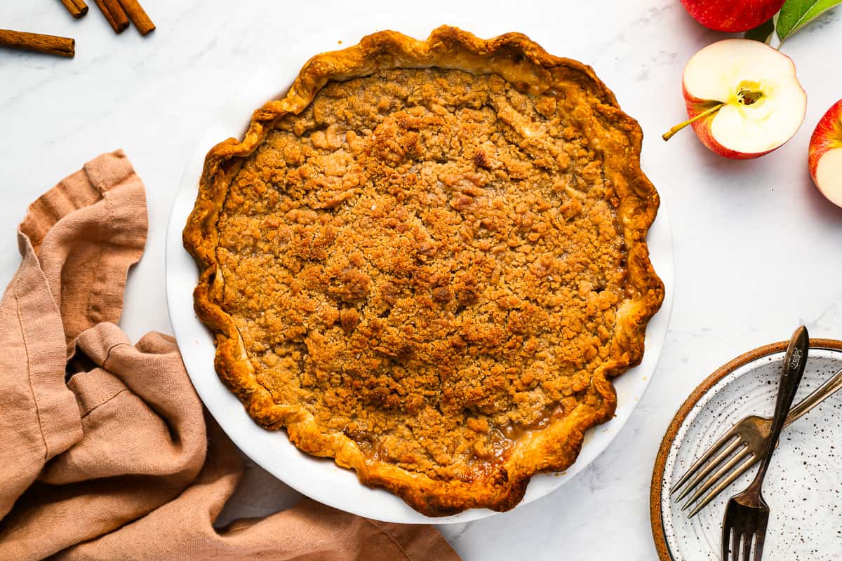 An apple pie with crumb topping in a pie plate.