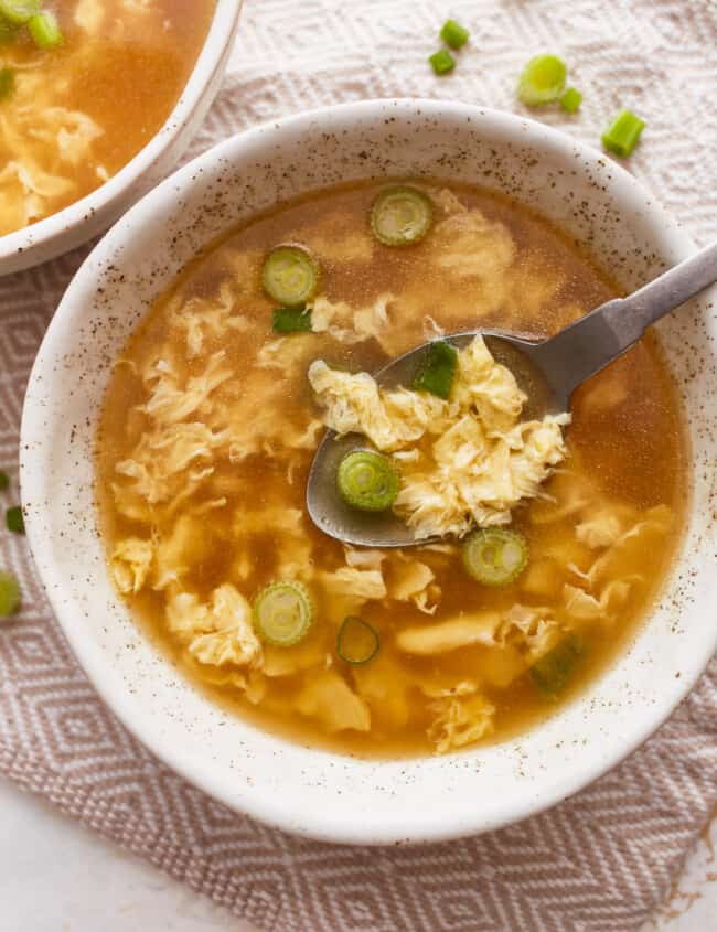 Two bowls of asian noodle soup with a spoon.