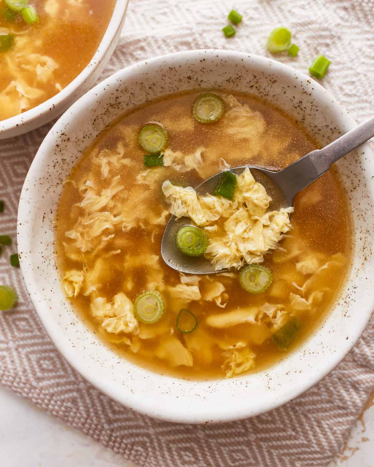 A bowl of egg drop soup with a spoon.