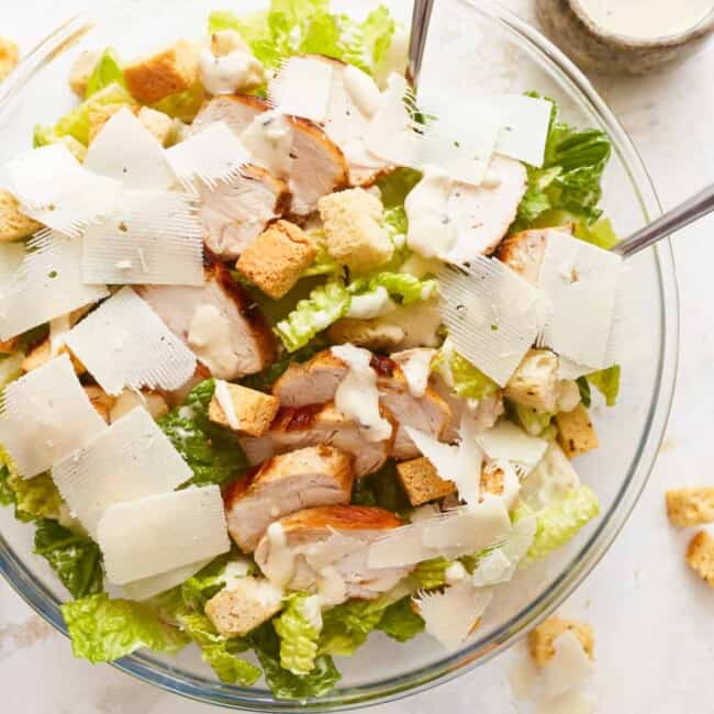 A bowl of chicken caesar salad with croutons.