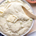 Mashed potatoes in a bowl with a wooden spoon.