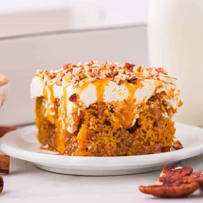 A slice of pumpkin cake on a plate next to a glass of milk.