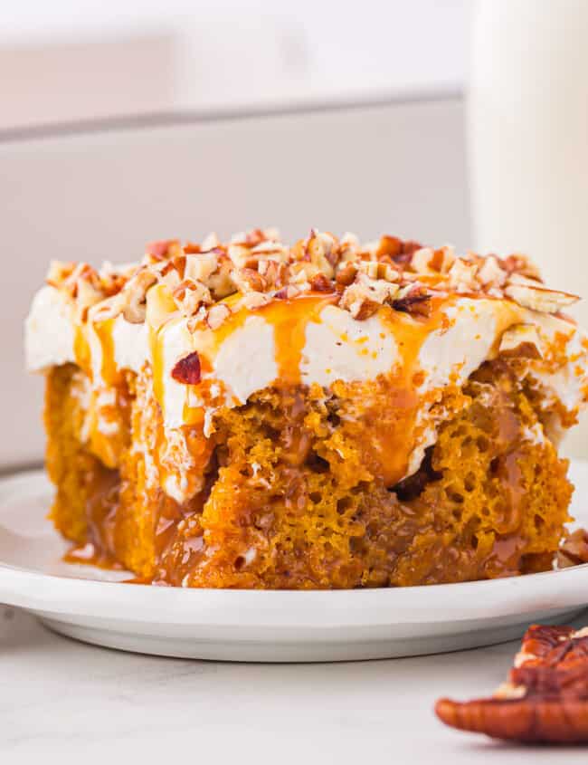 A slice of pumpkin cake on a plate next to a glass of milk.