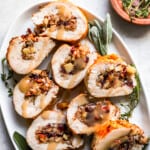 Turkey stuffed with cranberries and sage on a white plate.