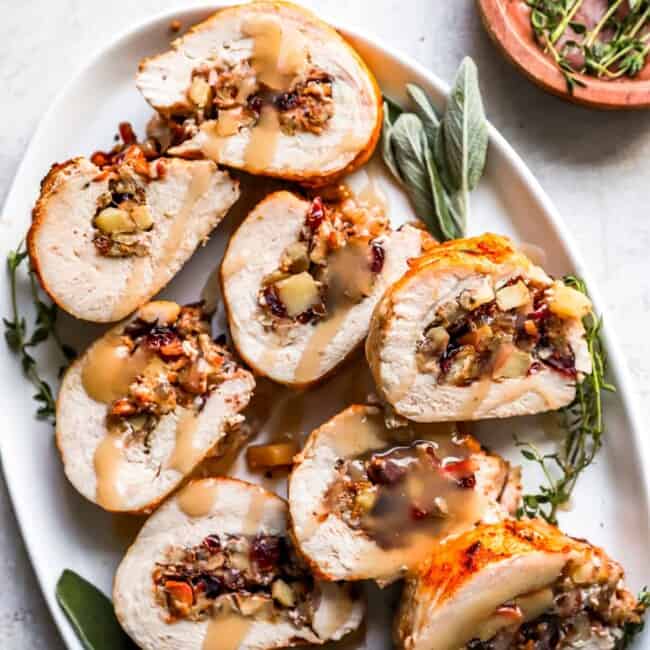 Turkey stuffed with cranberries and sage on a white plate.