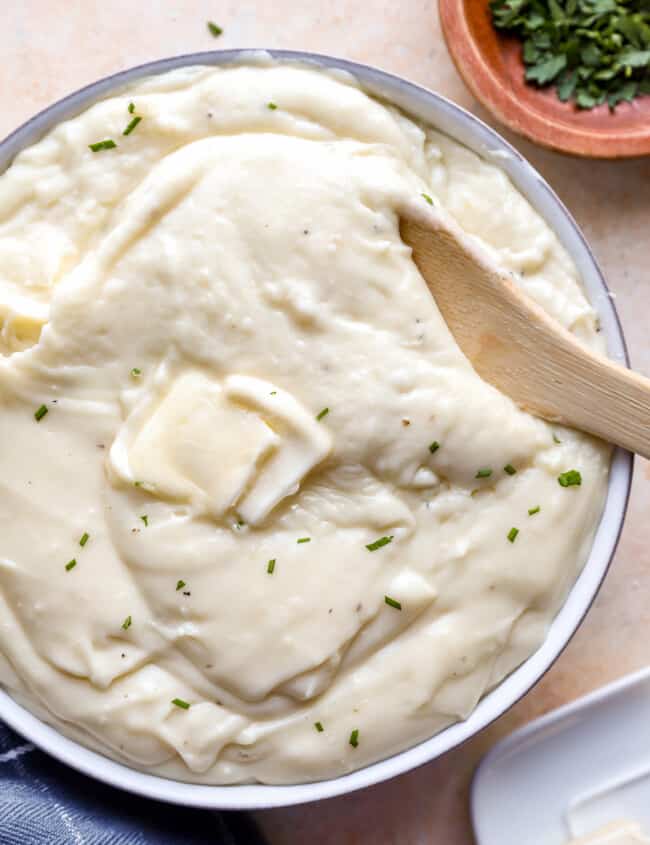 Mashed potatoes in a bowl with a wooden spoon.