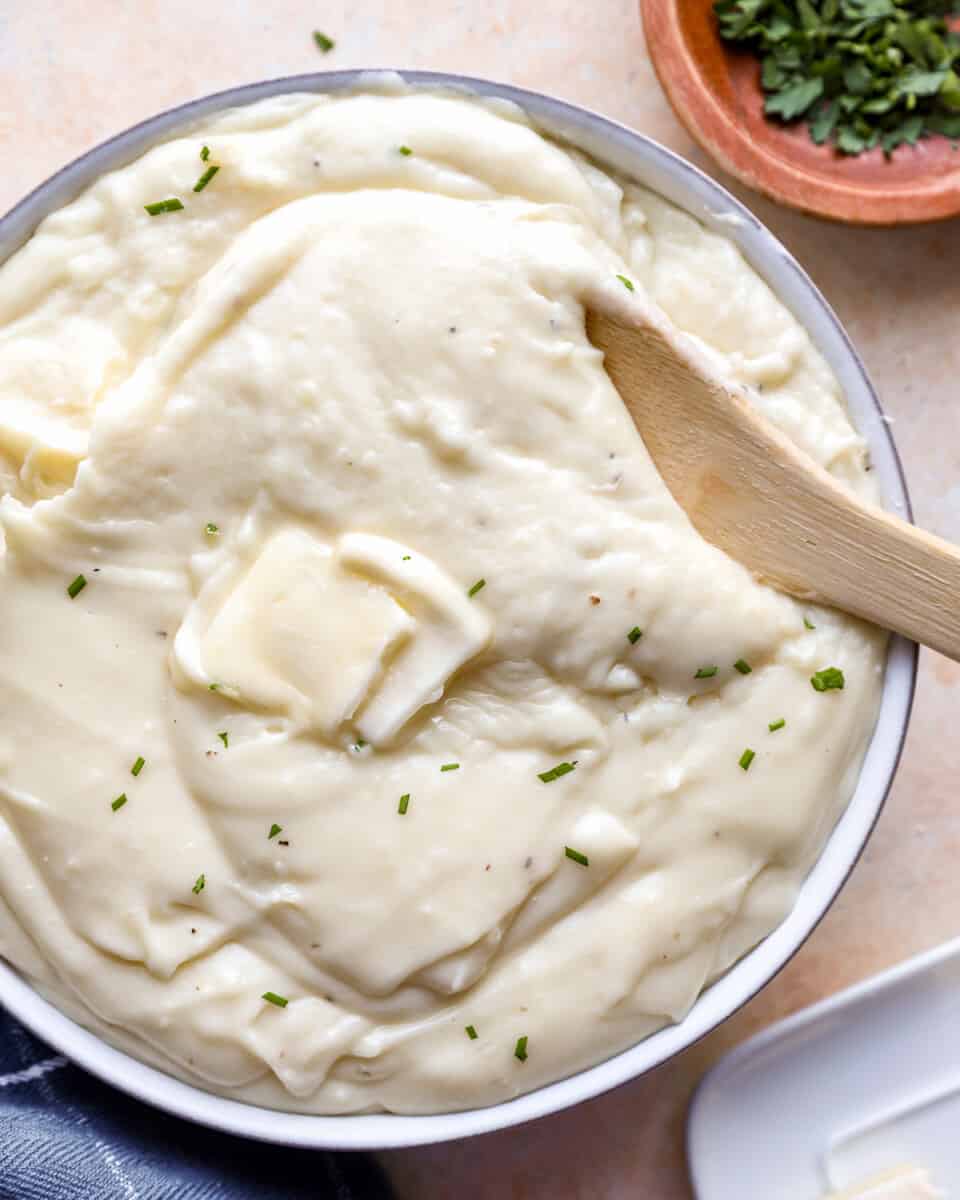 Fondue mashed potatoes (pommes aligot) in a bowl with a wooden spoon.
