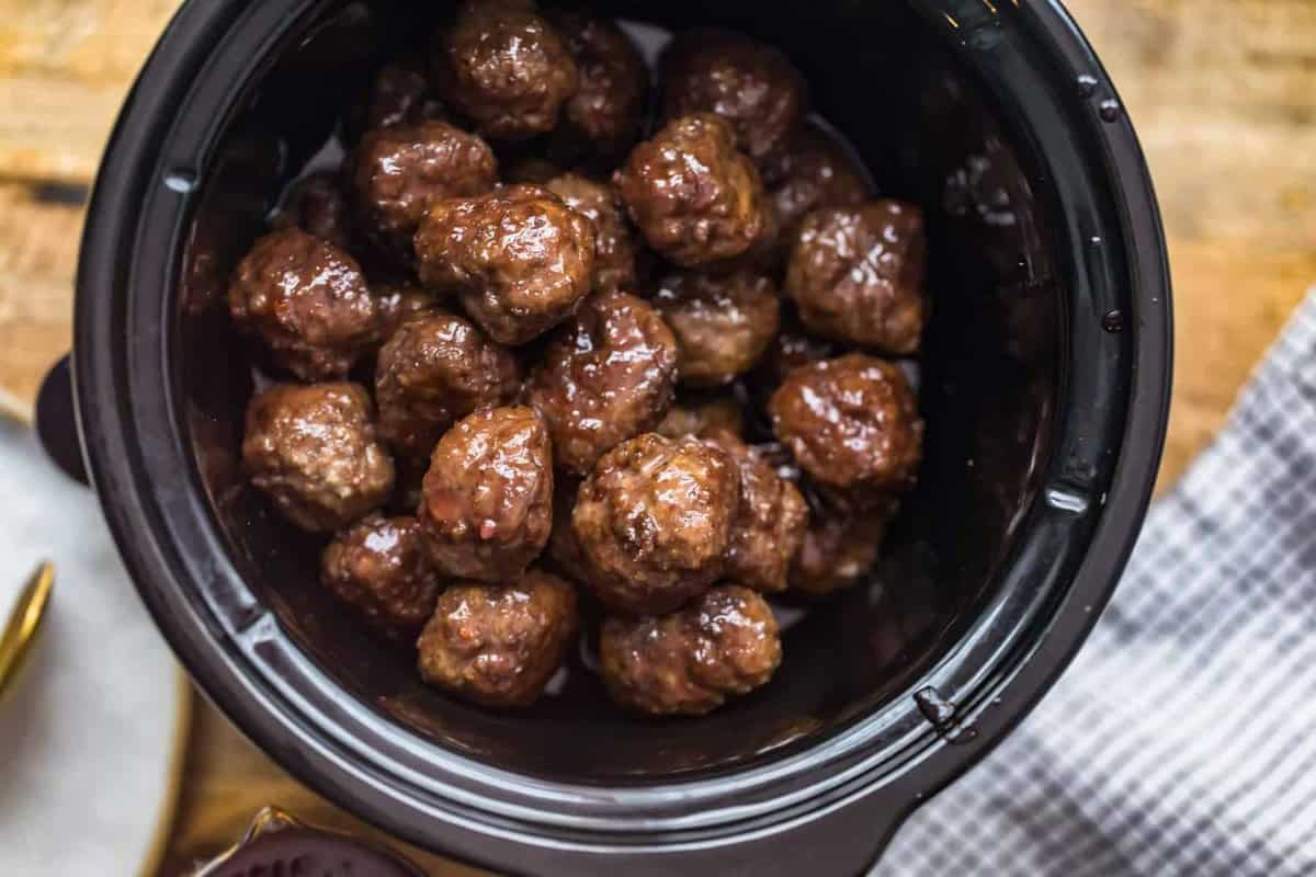 Grape jelly meatballs slow cooked on a wooden table.