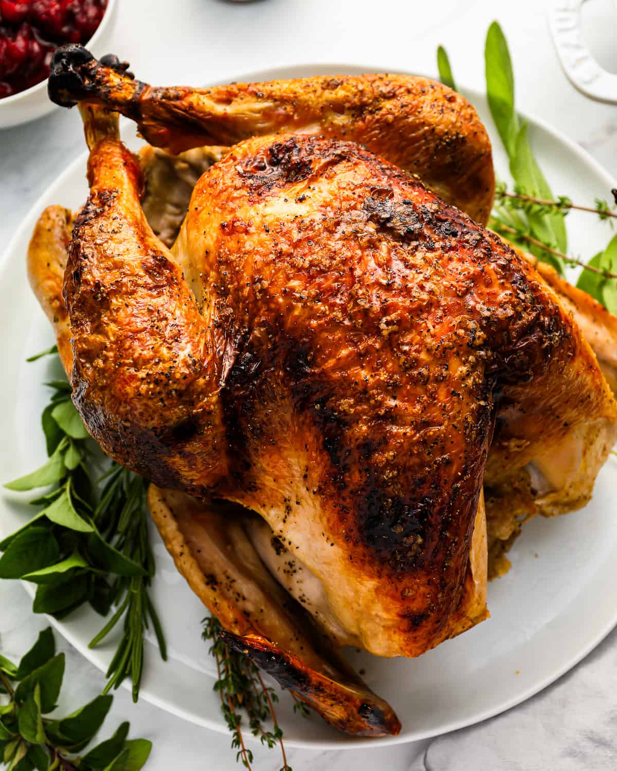 Roasted turkey on a white plate with sprigs of thyme.