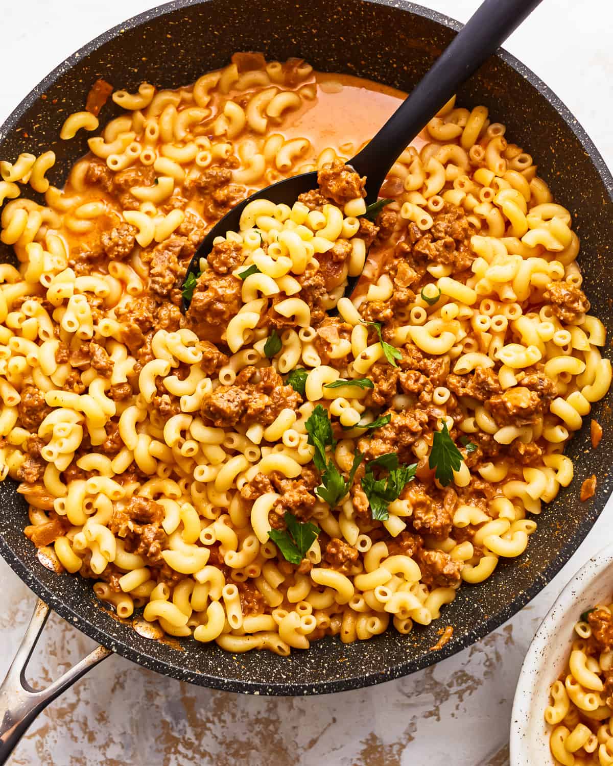 A skillet with hamburger helper and a black serving spoon.