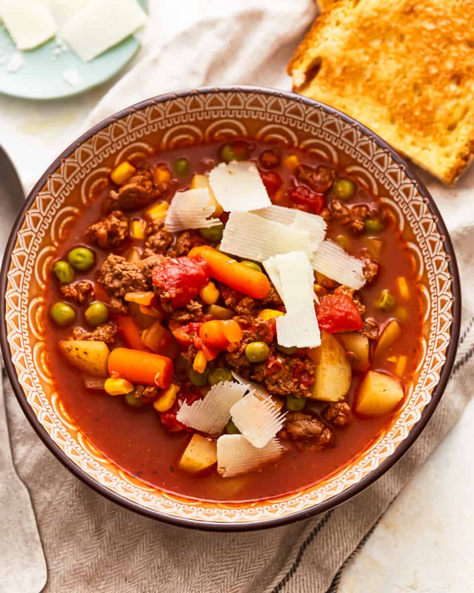A bowl of soup with meat, vegetables and bread.