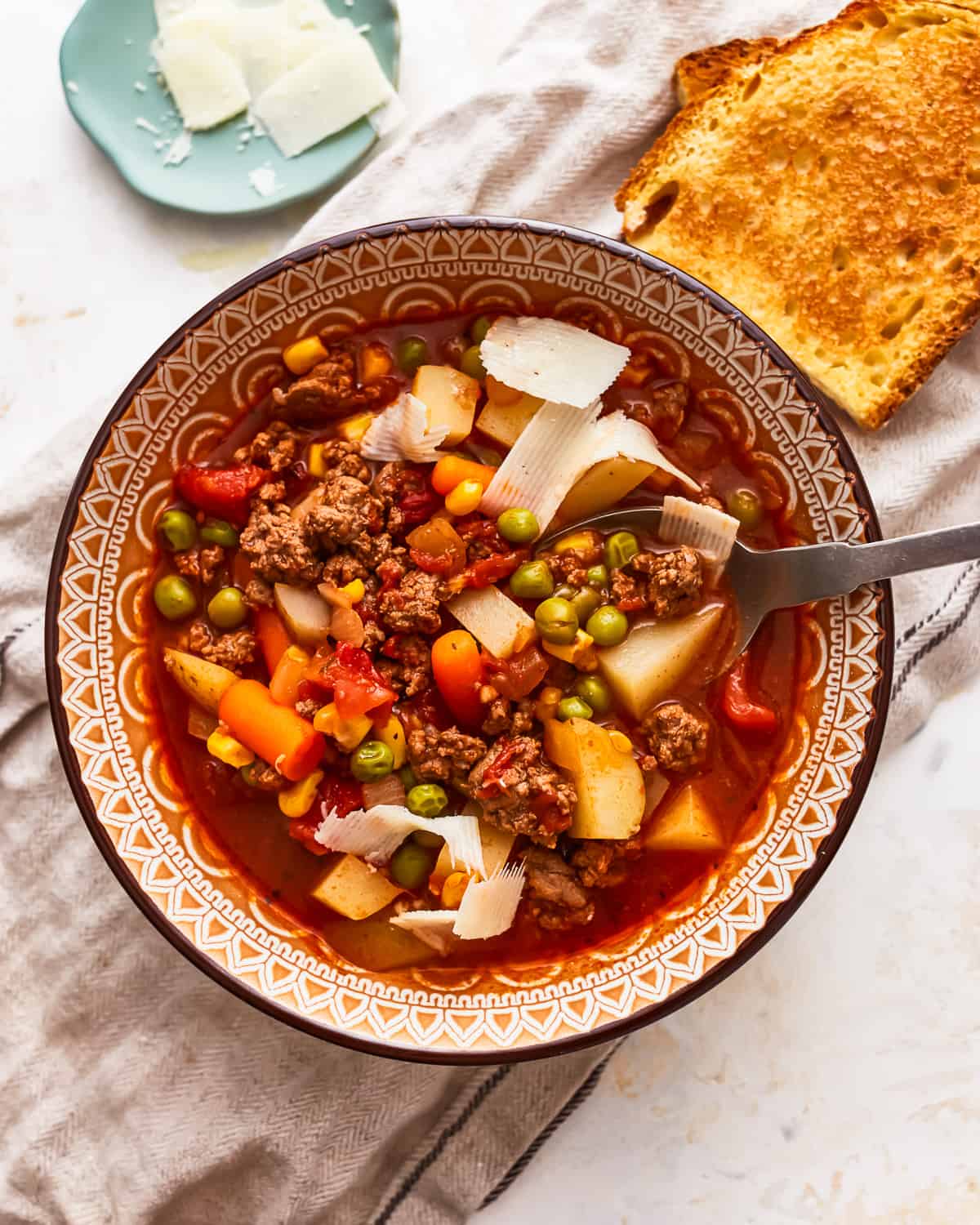 A bowl of soup with meat, vegetables and bread.