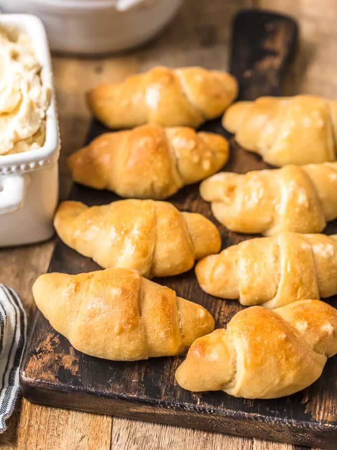 Homemade crescent rolls on a wooden cutting board.