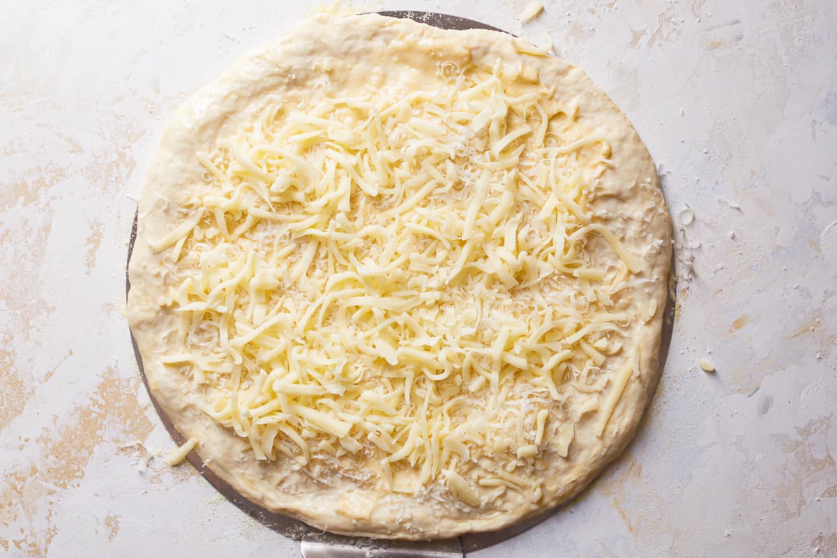 uncooked pizza topped with shredded cheese.