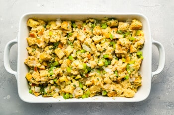 A white dish filled with stuffing and vegetables.