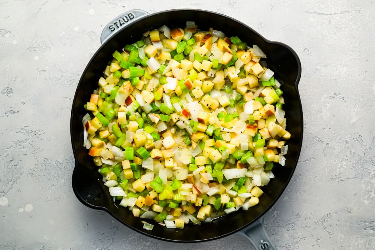 A skillet filled with onion, celery and apple pieces. - 7
