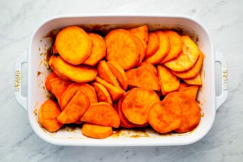 Sliced sweet potatoes in a white baking dish.