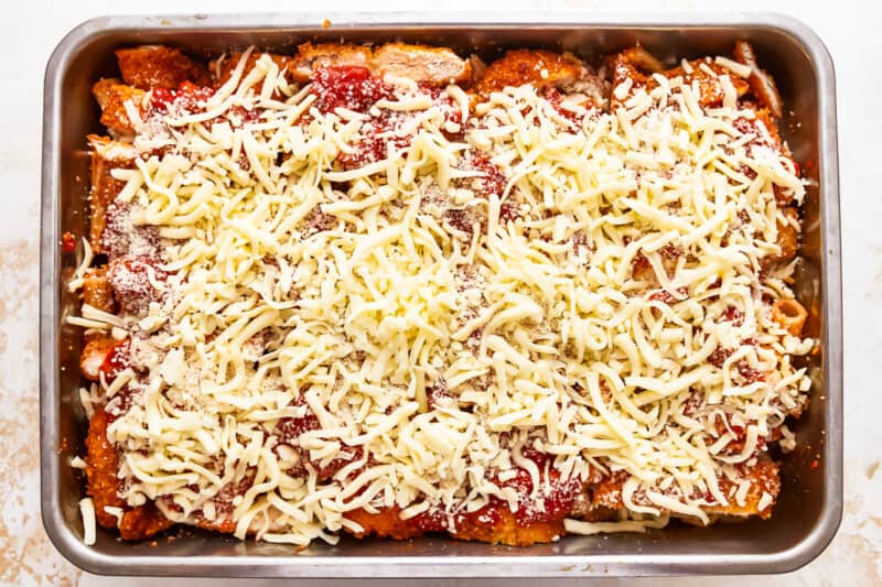 Enchiladas in a baking dish with cheese on top.