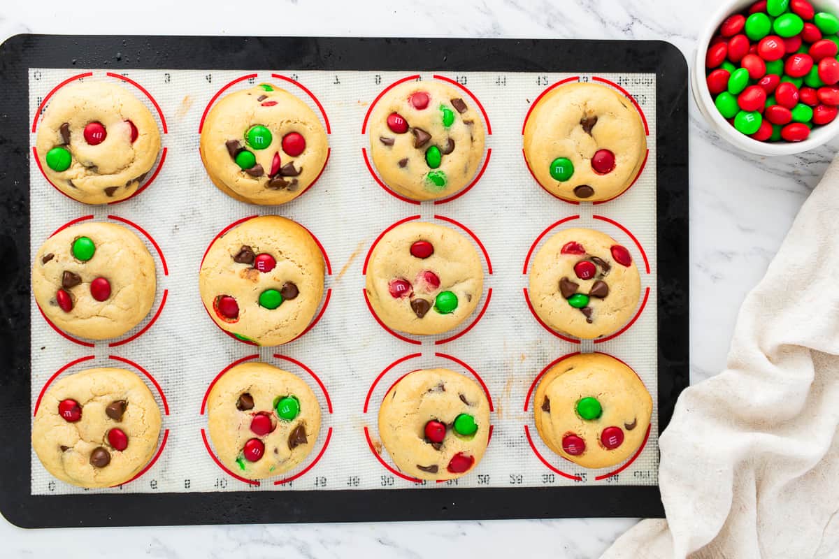 Christmas cookies on a baking sheet with red and green candies.