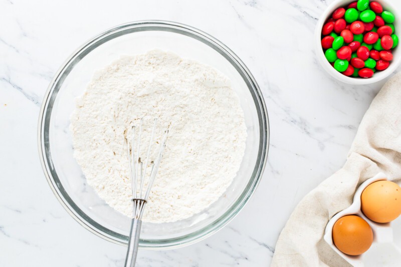 A bowl of flour, eggs, and other ingredients on a marble countertop.