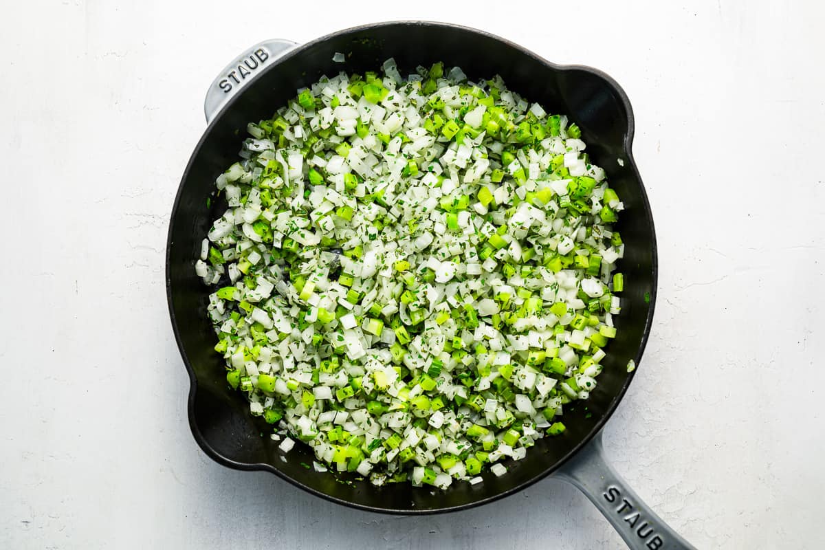 A frying pan filled with celery, onions, and garlic.