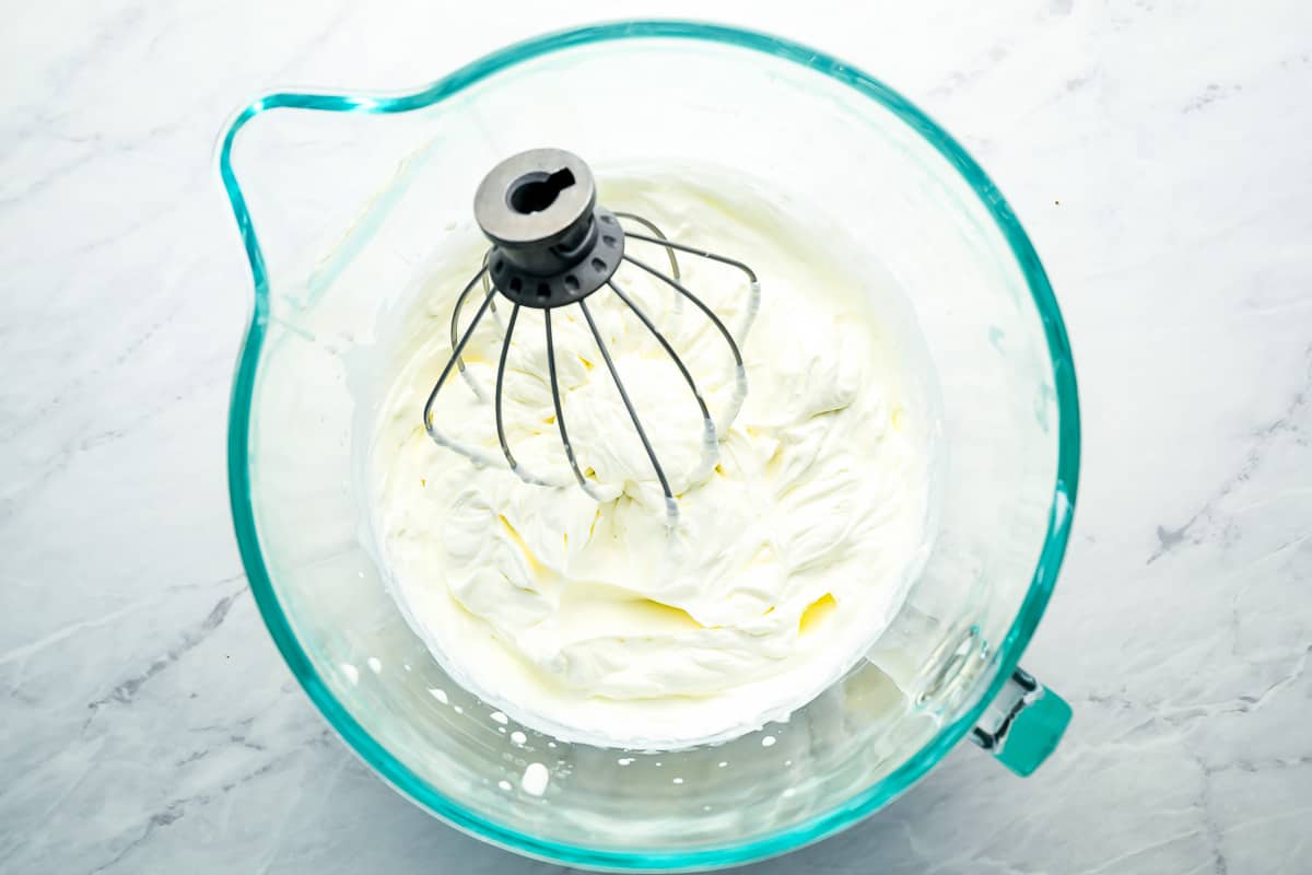 Whipping cream cheese and heavy cream in a glass measuring cup.