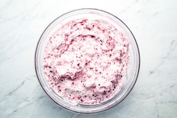 A bowl of raspberry cream cheese on a marble table.