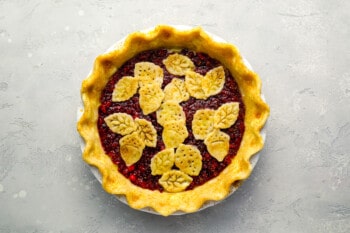 A pie with cranberries and leaves on top.