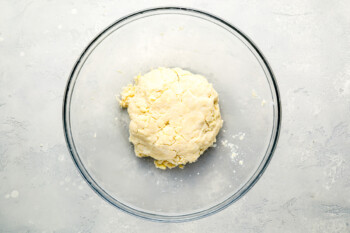 Dough in a glass bowl on a gray surface.