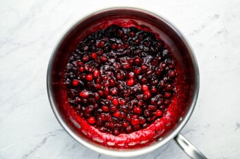 Cranberries in a pan on a marble countertop.