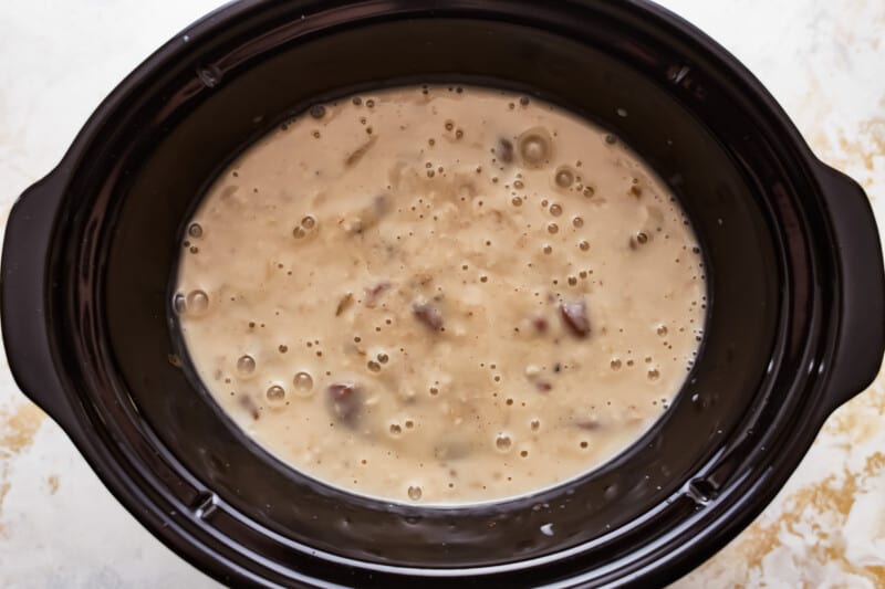 A black crock pot filled with soup.