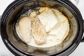 A crock pot filled with chicken and cheese.
