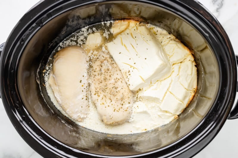 A crock pot filled with chicken and cheese.