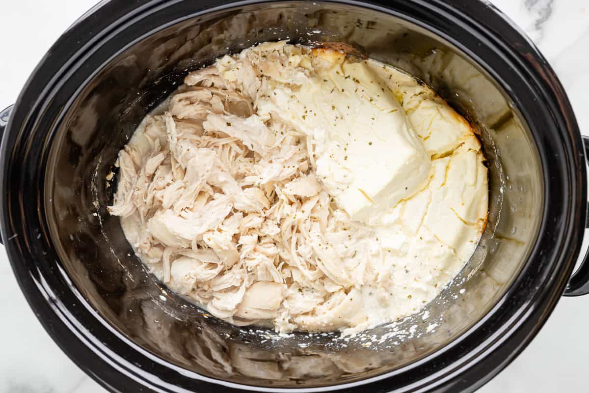 A crock pot filled with chicken and butter.