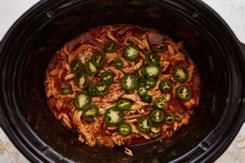 A slow cooker filled with chicken and jalapenos.